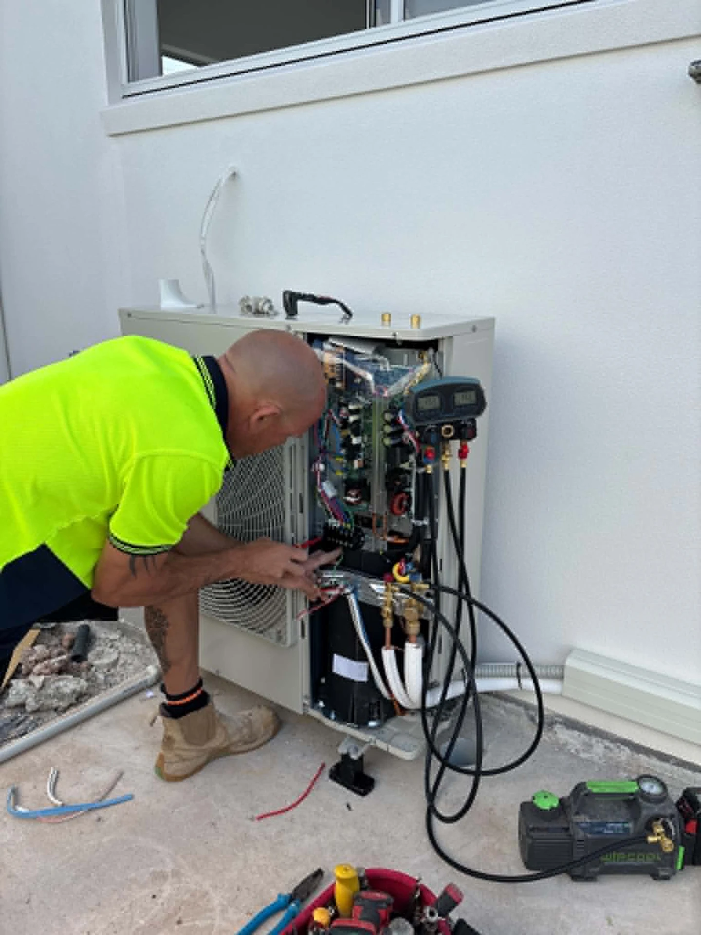 Millmac technician working on an outdoor air conditioning unit